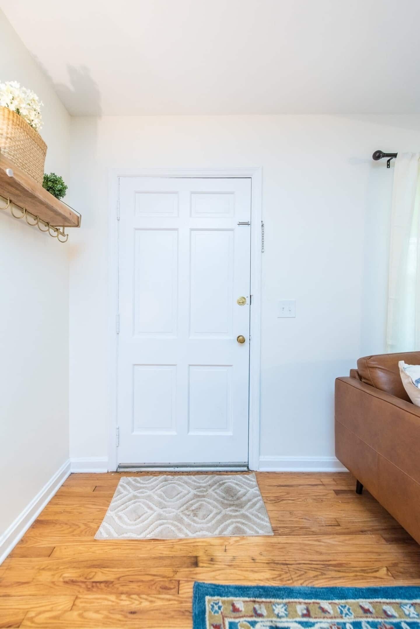A white door with a doorknob, a wooden floor, a brown couch, and a patterned rug.