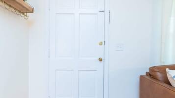 A white door with a doorknob, a wooden floor, a brown couch, and a patterned rug.