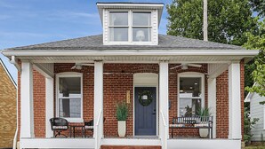 A two-story brick house with a front porch, a blue door, and a number '511' on the wall. - Washington Guest House (Washington)