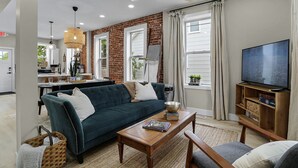 A modern living room with a sofa, coffee table, and TV stand. - Washington Guest House (Washington)