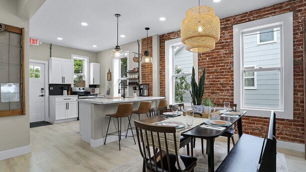 A modern kitchen with white cabinets, a central island, and pendant lighting. - Washington Guest House (Washington)
