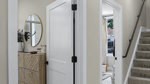 A hallway with a white door, a mirror, and a staircase. - Washington Guest House (Washington)