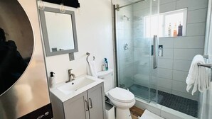 A modern bathroom with a glass shower enclosure, a white sink, and a toilet.