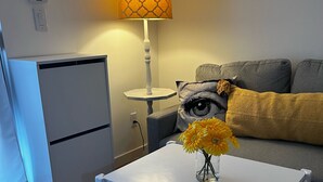 A modern living room with a white table, a grey sofa, and a lamp.