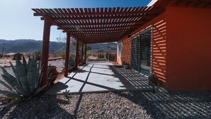 A covered outdoor area with a pergola, a concrete pathway, and a view of mountains.