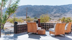 An outdoor seating area with wicker furniture and a view of mountains.