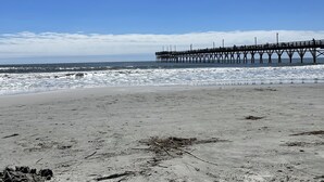 Una playa con un muelle que se adentra en el océano.