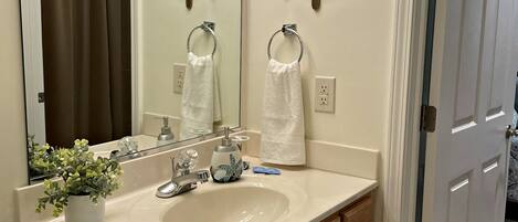 A bathroom with a sink, vanity, and two ship wheel decorations.