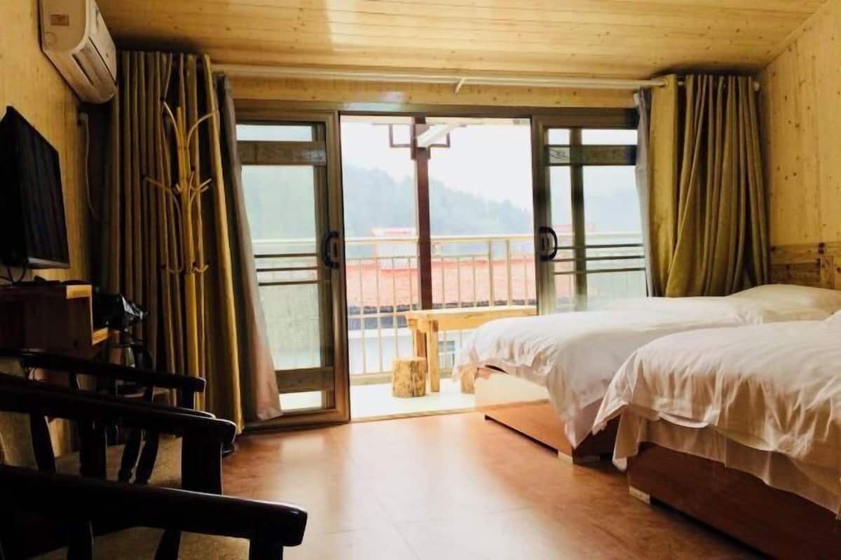 Ein Zimmer mit zwei Betten, einem Schreibtisch und einem Balkon mit Blick.