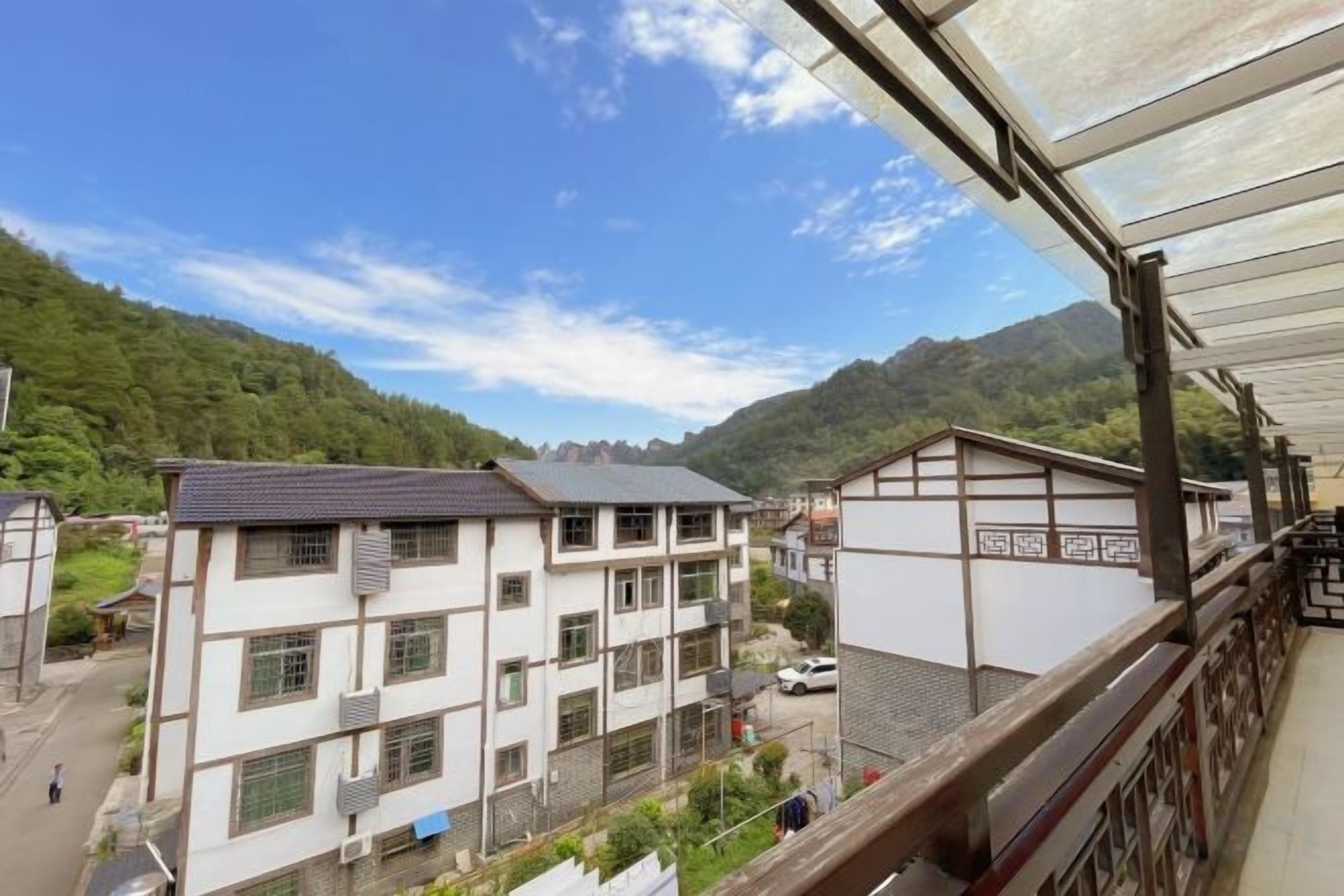 A residential building with multiple floors, a balcony, and a view of a mountainous landscape.