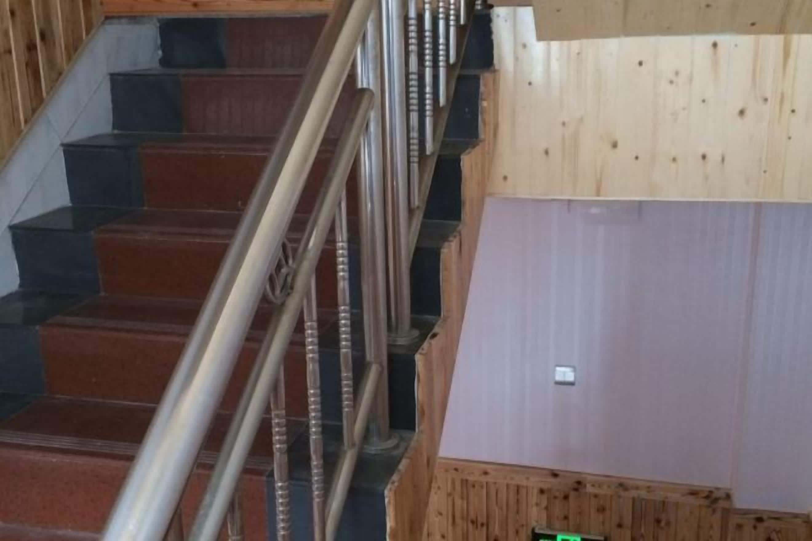 Una escalera con barandilla de metal y piso de madera.
