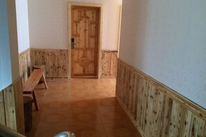 A hallway with a wooden door, a bench, and a tiled floor.