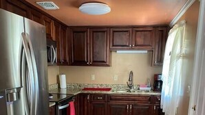 A kitchen with wooden cabinets, a stainless steel refrigerator, and a tiled floor. - Conveniently located 2brm / 1bt Home (Myrtle Grove)