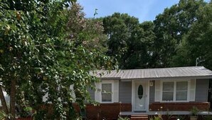 A house with a front porch, a gravel driveway, and a white picket fence. - Conveniently located 2brm / 1bt Home (Myrtle Grove)