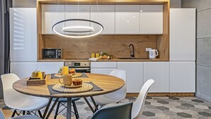 Une cuisine moderne avec des meubles blancs, un plan de travail en bois et une table de salle à manger ronde, assortie de chaises.