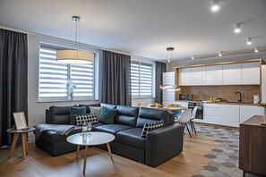 Relax in this stylish living space with a large sofa, coffee table, and adjacent kitchen.