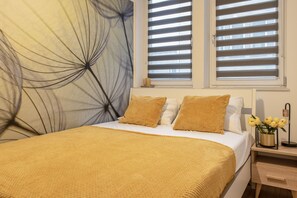 Relax in a serene bedroom with a large bed, nightstand, and modern lamp, surrounded by a beautiful abstract painting.