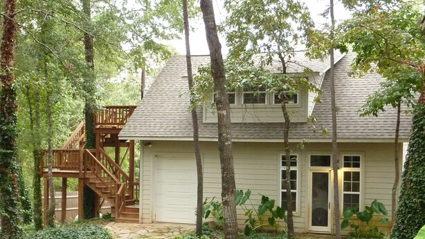 Une maison dotée d’une terrasse en bois et d’un chemin de pierre menant à la porte d’entrée.