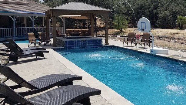 Una piscina amb gandules, una zona de seients coberta i un cèrcol de bàsquet.