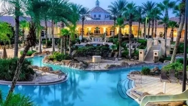 Un complexe hôtelier doté d’une piscine, de palmiers et d’un bâtiment surmonté d’un dôme.