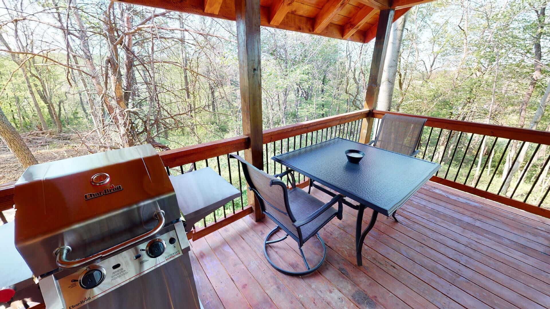 A covered outdoor area with a Char-Broil grill, a table, and chairs.
