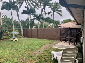 A backyard with a patio area, a wooden fence, and a table with chairs.