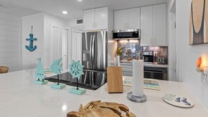 Une cuisine moderne avec des meubles blancs, des appareils en acier inoxydable et une décoration sur le thème de la marine.