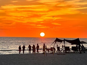 A beach scene with people and tents at sunset.