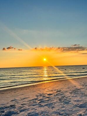 A beach at sunset with the sun reflecting on the water. - Close to beach, private heated pool, bikes, beach chairs & more! (Holmes Beach)