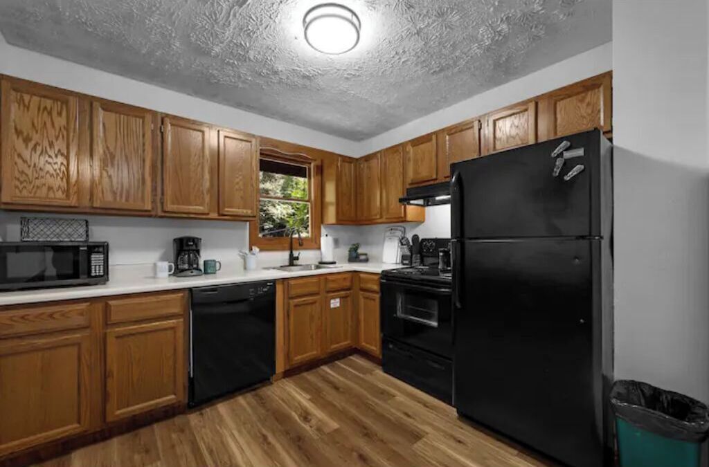 A kitchen with wooden cabinets, a black refrigerator, a dishwasher, and a microwave.