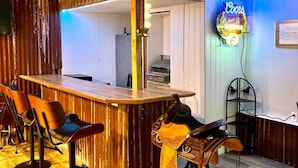 En bar med barstole, et neonskilt og et spejl.