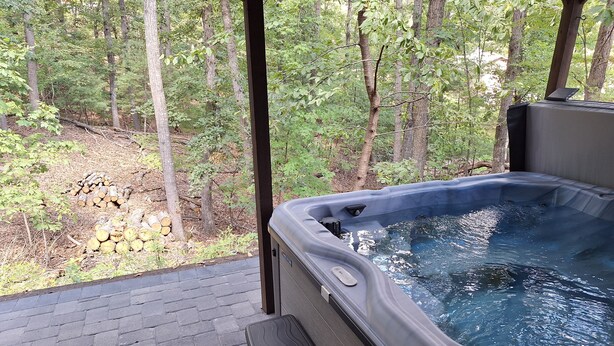 Ein Whirlpool mit einer Holzterrasse und Blick auf ein bewaldetes Gebiet.