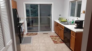 Eine kompakte Küche mit einer Schiebetür zum Balkon, Holzschränken und einem Geschirrspüler.