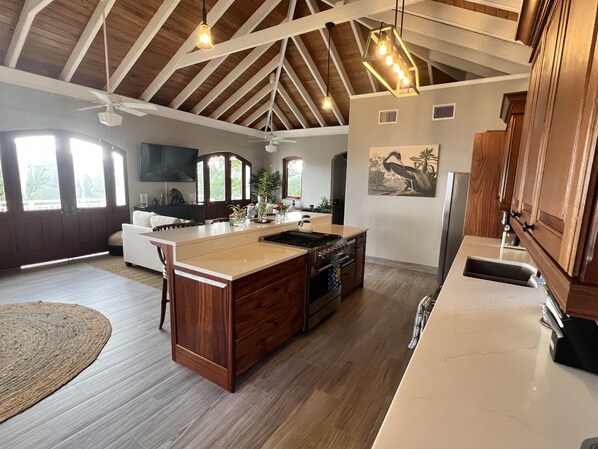 Una cocina espaciosa con una isla grande, armarios de madera y un techo alto con vigas a la vista.