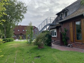 Um imóvel residencial com casa de tijolos, porta de madeira, escadaria e pequeno jardim.