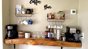 Una encimera de cocina con equipo para preparar café, tazas y recipientes de almacenamiento.