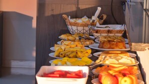 Una mesa de buffet con diversos alimentos, como frutas, pasteles y pan.
