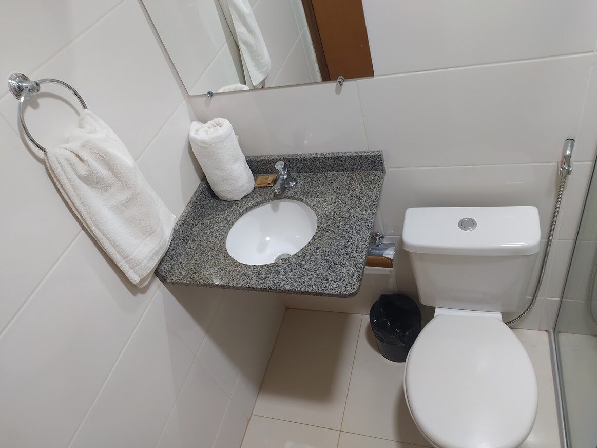 Casa de banho com lavatório branco, sanita e chuveiro.