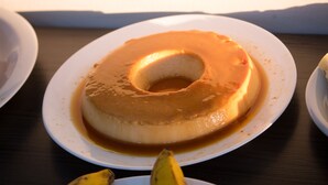 Un flan de caramelo sobre un plato blanco, con una banana en la mesa.