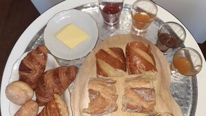 Una bandeja con varios pasteles, una pequeña porción de mantequilla y pequeños recipientes con mermelada y miel.