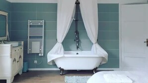 Un baño con bañera, tocador blanco, espejo, toallero y cortina de ducha.