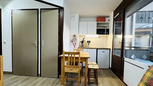 Un espacio habitable compacto con comedor, kitchenette y sofá.