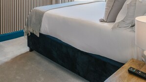 A bedroom with a bed, a TV mounted on the wall, a window with curtains, and a ceiling with exposed beams. - Haar with Rooms (St. Andrews)