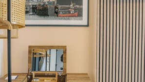 A wooden desk with a mirror, a blue ottoman, and a framed picture of a harbor scene. - Haar with Rooms (St. Andrews)