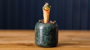 A green marble vase with a tall, slender object inside, possibly a candle or a decorative item, on a wooden surface against a dark background. - Haar with Rooms (St. Andrews)