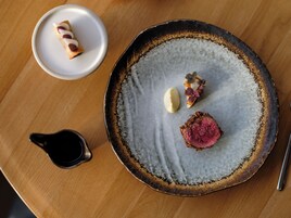 Una mesa de comedor con un plato de comida, un bol pequeño y una taza.