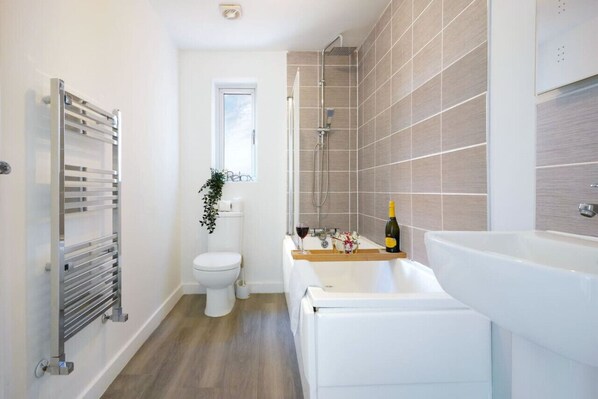 A modern bathroom with a toilet, shower, and bathtub.