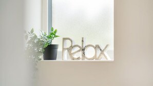 A window sill with a potted plant and the word "Relax" in a decorative font. - Detached House • Free Parking • FastWifi • SmartTV (Northampton)