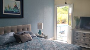 Un dormitorio con una cama, televisión, cómoda, lámpara y un cuadro en la pared.