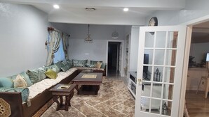 Una sala de estar con sofá, mesa de centro y televisor al fondo.
